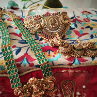 N03071_ Grand classic matte gold polished temple jewelry choker style and Long Haram crafted design gold plated necklace set embellished with ruby and green stones .