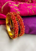 B0274_Lovely golden pearl bangles with delicate craftwork embellished with a bunch of red beads.