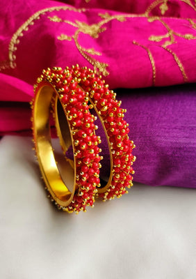 B0274_Lovely golden pearl bangles with delicate craftwork embellished with a bunch of red beads.