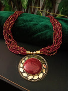 N0248_ Classic Off beat necklace with over sized circular pendant with a maroon color stone with beautiful craft work followed by layered bead chains.