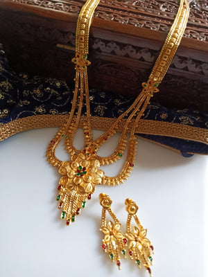 N0176_Ravishing traditional style Gold plated long layered grand necklace set with fine artwork of floral designs studded with pink and green ruby stones with a touch of broad chain drop pendant.