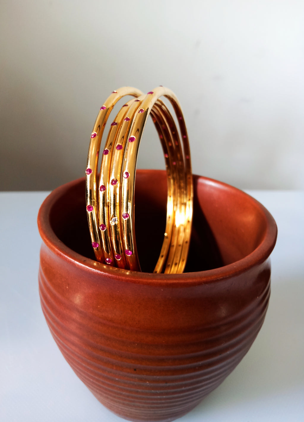 B0226_Beautiful sleek design  golden bangles with a touch of pink stones.