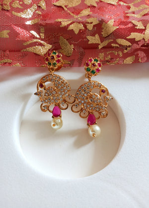 E0667_Beautiful crafted peacock design earrings studded with American diamond stones with a touch of pink & green stones with pearl drops.